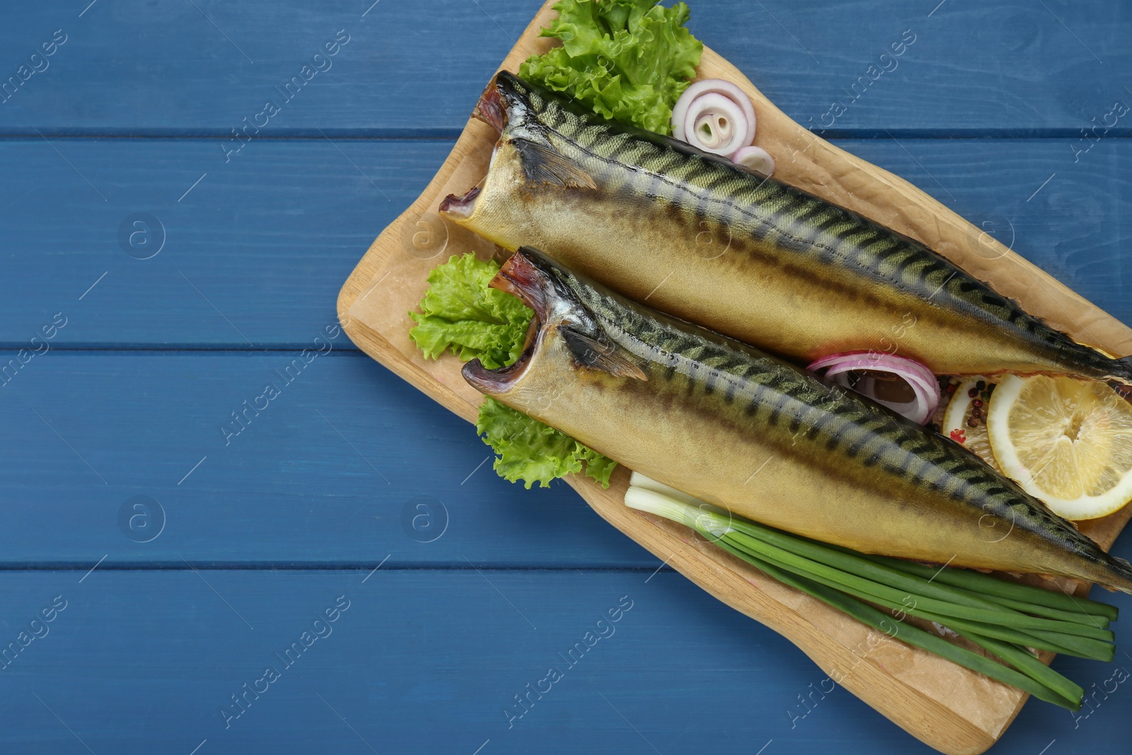 Photo of Delicious smoked mackerels and products on blue wooden table, top view. Space for text