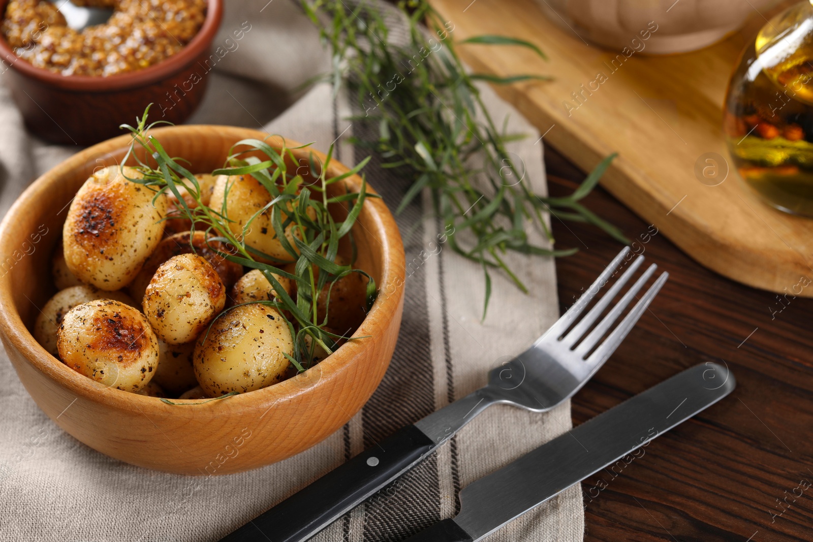 Photo of Delicious grilled potatoes with tarragon on wooden table