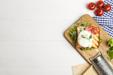 Photo of Delicious poached egg sandwich served on white wooden table, flat lay. Space for text