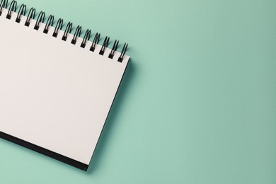 Photo of Blank notebook on turquoise background, top view. Space for text