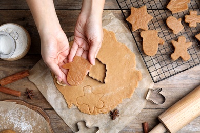 Woman making Christmas cookies at wooden table, top view