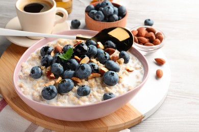 Photo of Tasty oatmeal porridge and ingredients served on wooden table. Healthy meal