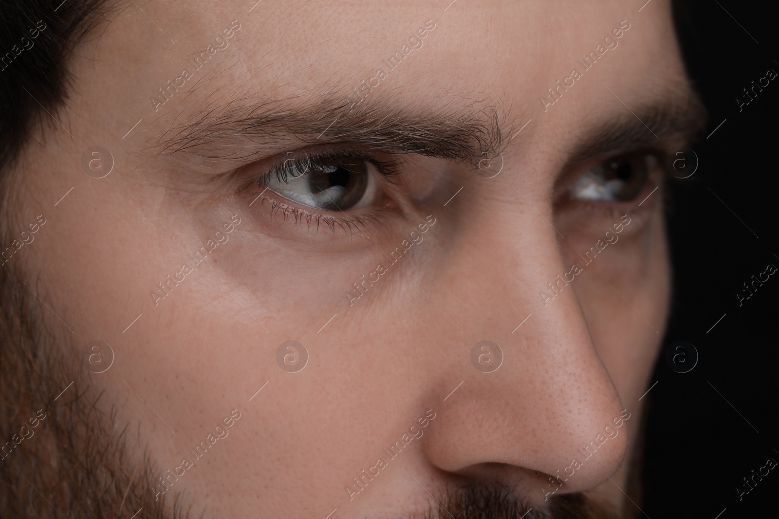 Photo of Evil eye. Man with scary eyes on black background, closeup