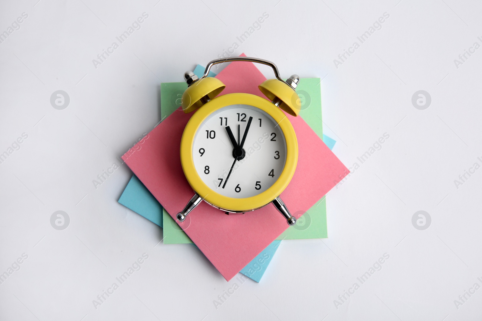 Photo of Alarm clock and reminder notes on light grey background, top view