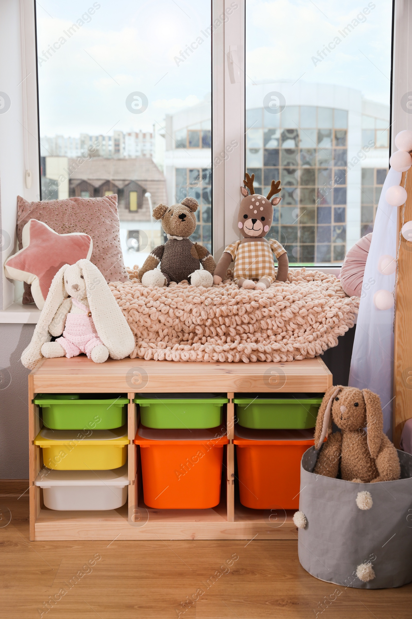 Photo of Stylish child room with storage for toys near window