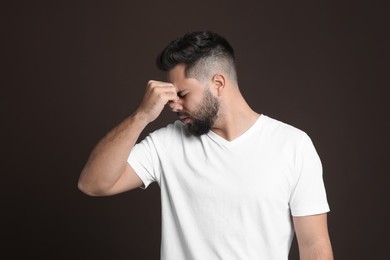 Photo of Young man suffering from headache on dark background