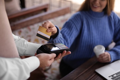 Photo of Woman with credit card using payment terminal at restaurant, closeup