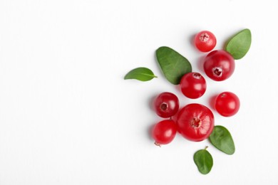 Photo of Fresh ripe cranberries and green leaves on white background, flat lay. Space for text