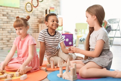 Cute little children playing with wooden blocks indoors