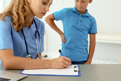 Photo of Female medical assistant consulting child in clinic