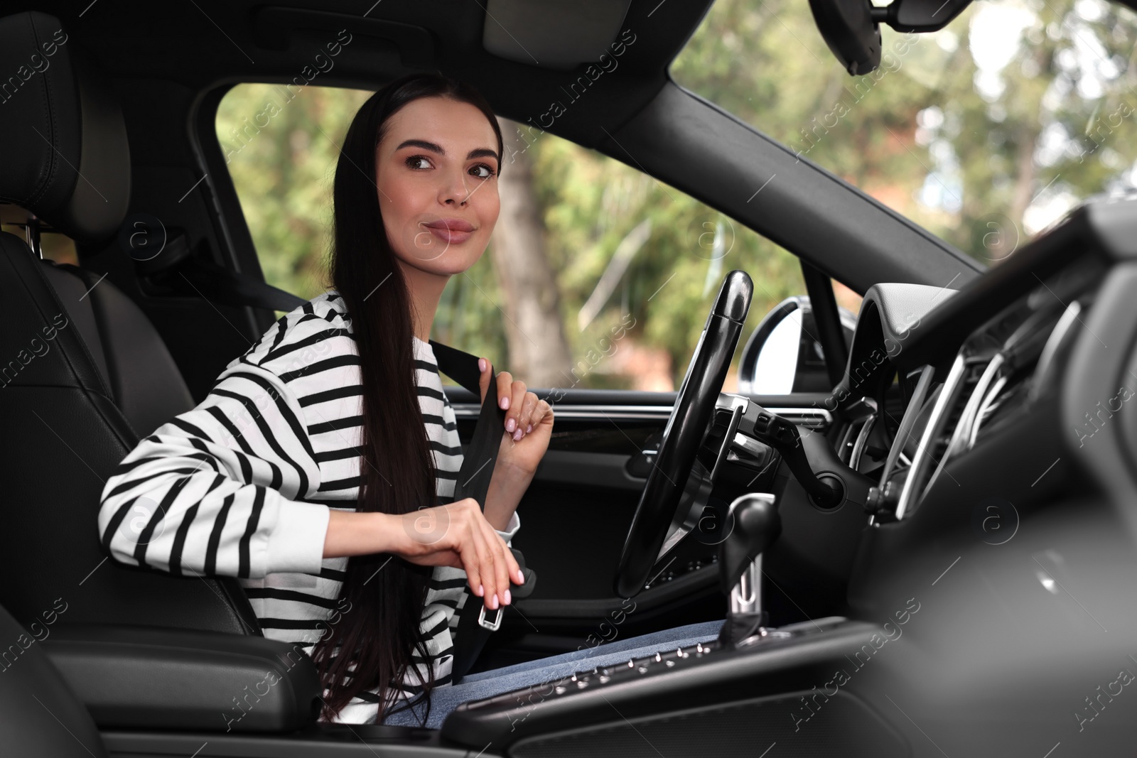 Photo of Woman fastening safety seat belt inside modern car