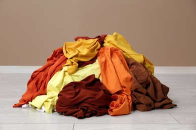 Pile of dirty clothes on floor near light brown wall indoors