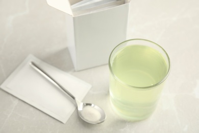 Medicine sachet, spoon and glass with dissolved drug on table indoors