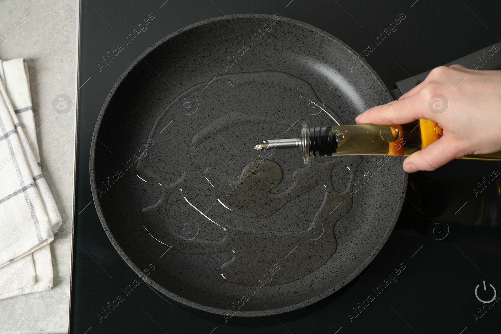 Photo of Woman pouring cooking oil from bottle into frying pan, top view