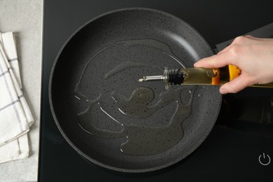 Photo of Woman pouring cooking oil from bottle into frying pan, top view