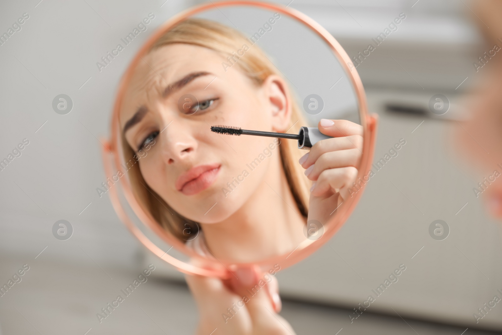 Photo of Young woman with eyelash loss problem applying mascara indoors