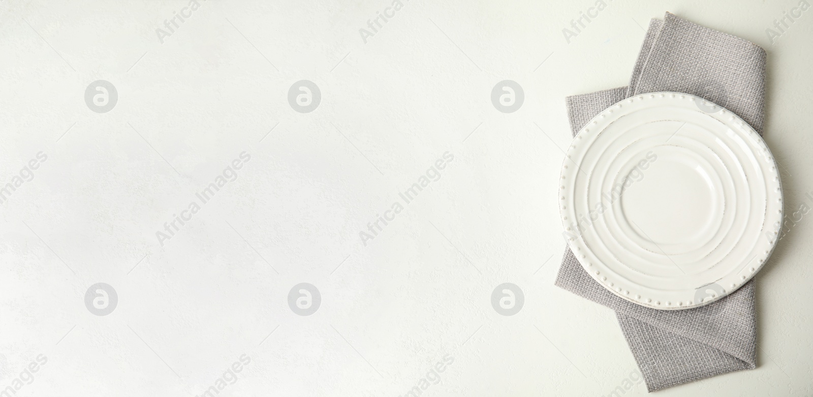 Photo of Empty plate and napkin on white table, top view. Space for text