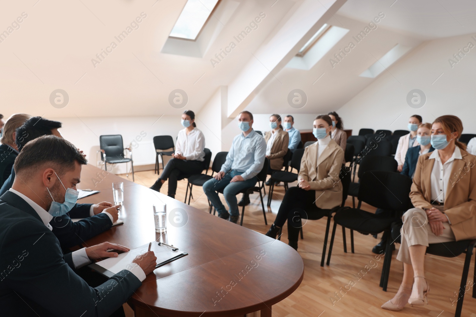 Photo of Business conference. People with protective masks listening to speaker report