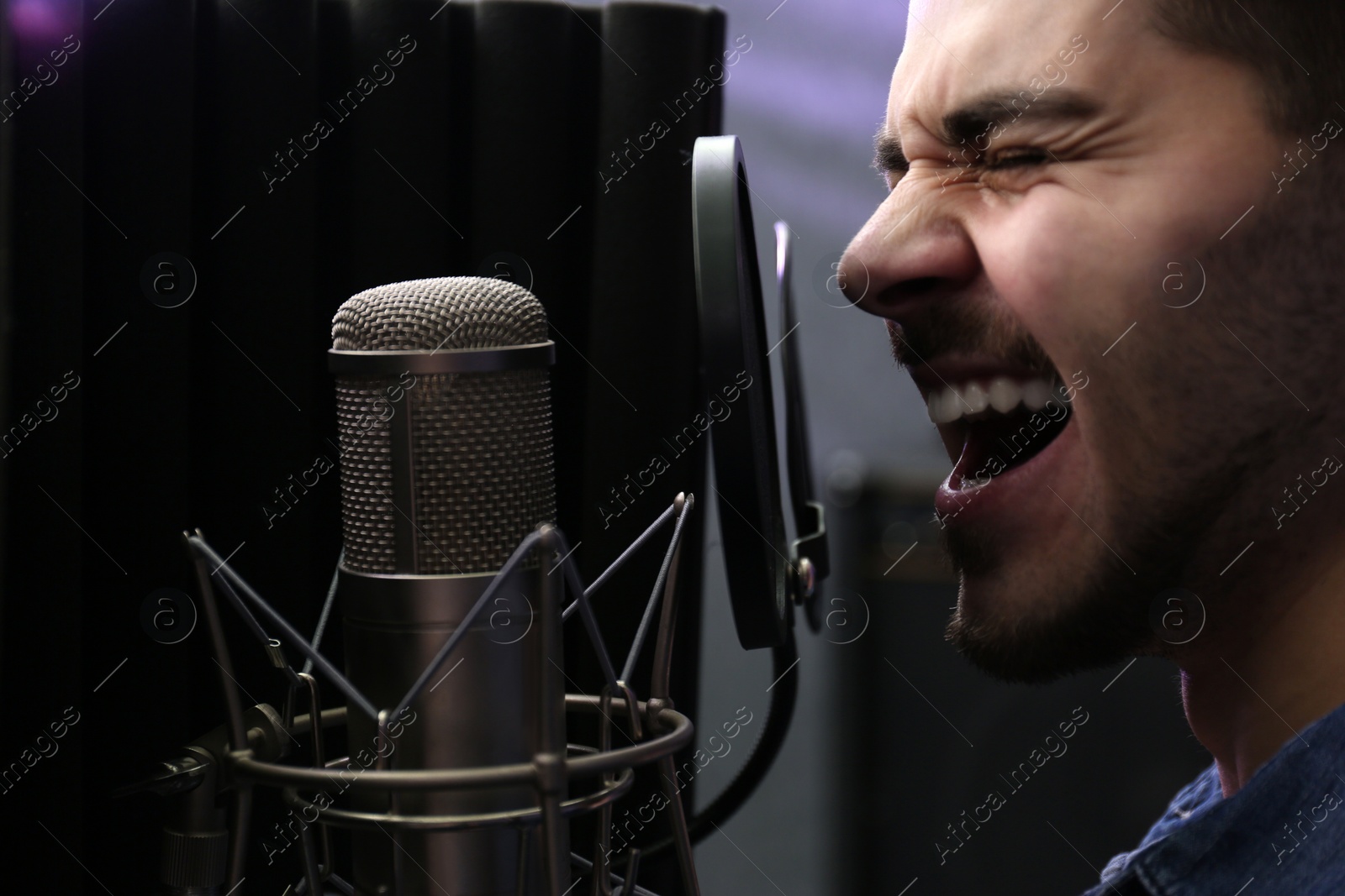 Photo of Young singer with microphone recording song in studio