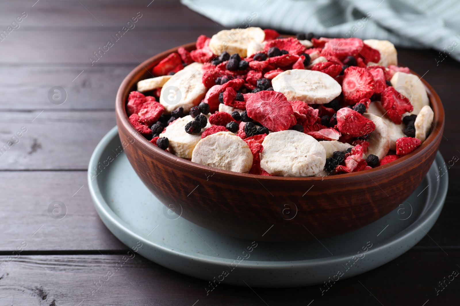 Photo of Bowl of different freeze dried fruits on wooden table, closeup