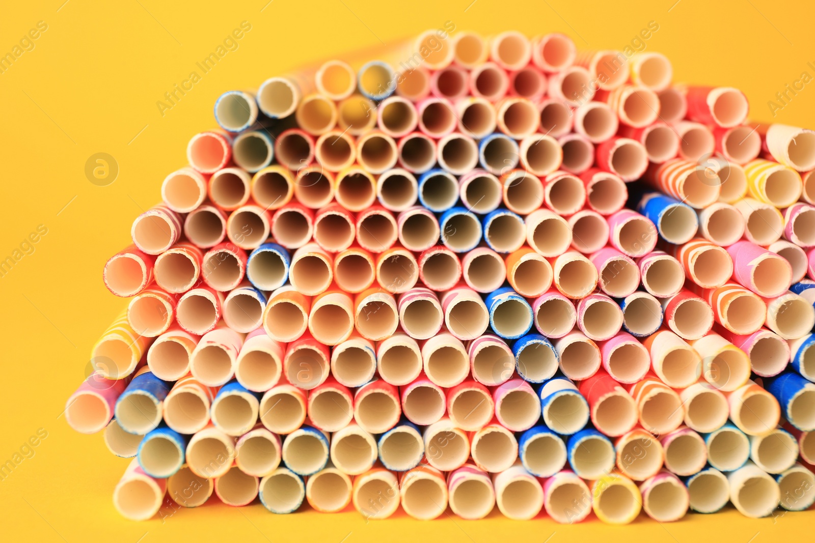 Photo of Many paper drinking straws on yellow background, closeup