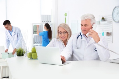 Photo of Mature female receptionist and senior male doctor working in hospital