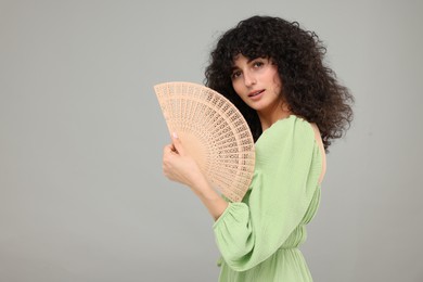 Photo of Woman holding hand fan on light grey background. Space for text