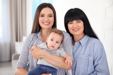 Photo of Portrait of young woman, her baby and mature mother indoors
