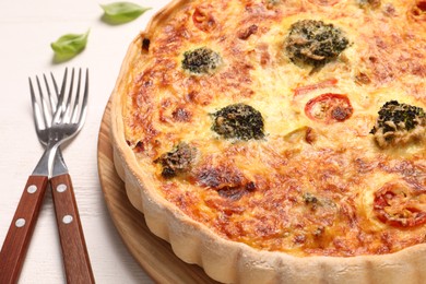 Photo of Delicious homemade vegetable quiche and forks on wooden table, closeup