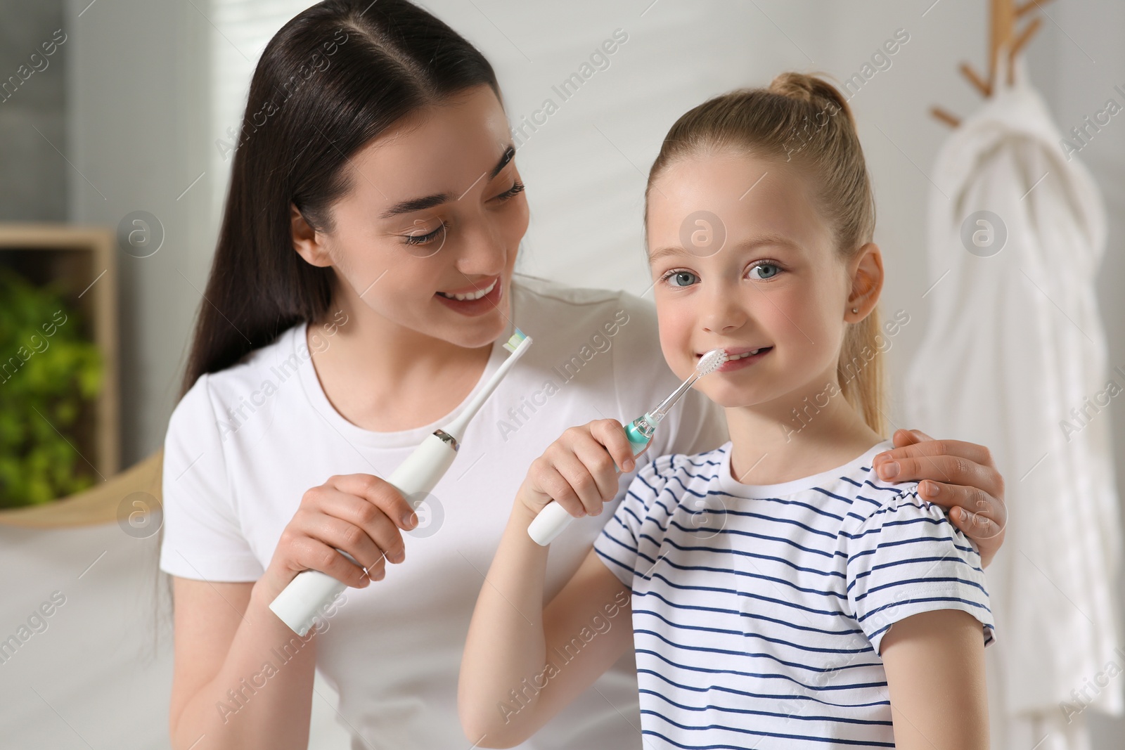 Photo of Mother and her daughter brushing teeth together in bathroom