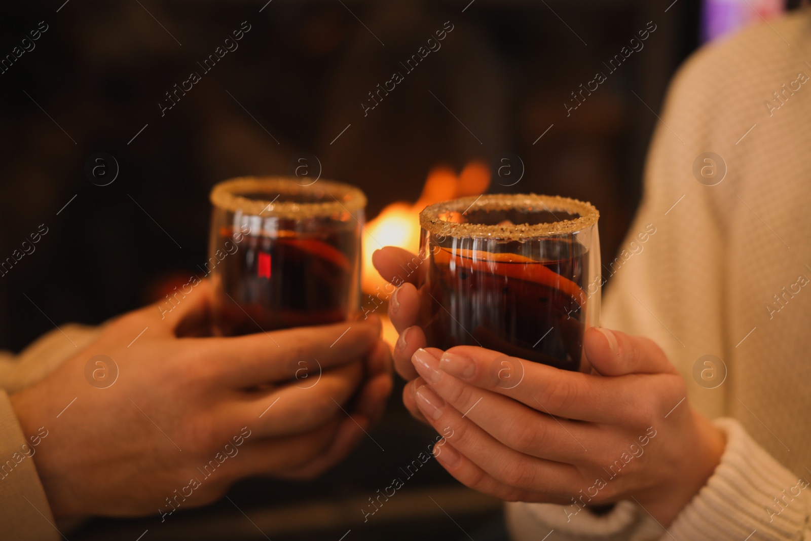 Photo of Couple with tasty mulled wine near fireplace indoors, closeup