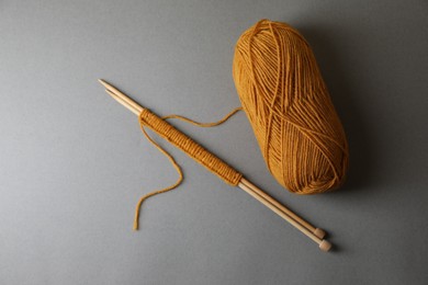 Photo of Soft orange yarn and knitting with needles on light grey background, top view