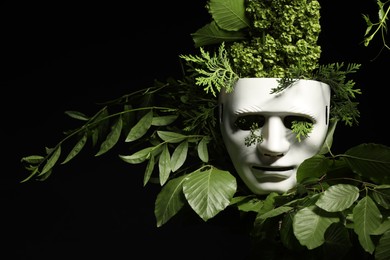 Photo of Theatrical performance. Plastic mask and floral decor on black background