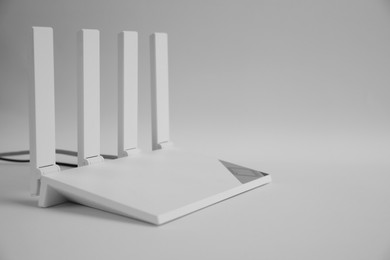 Photo of Modern Wi-Fi router on light grey background. Space for text