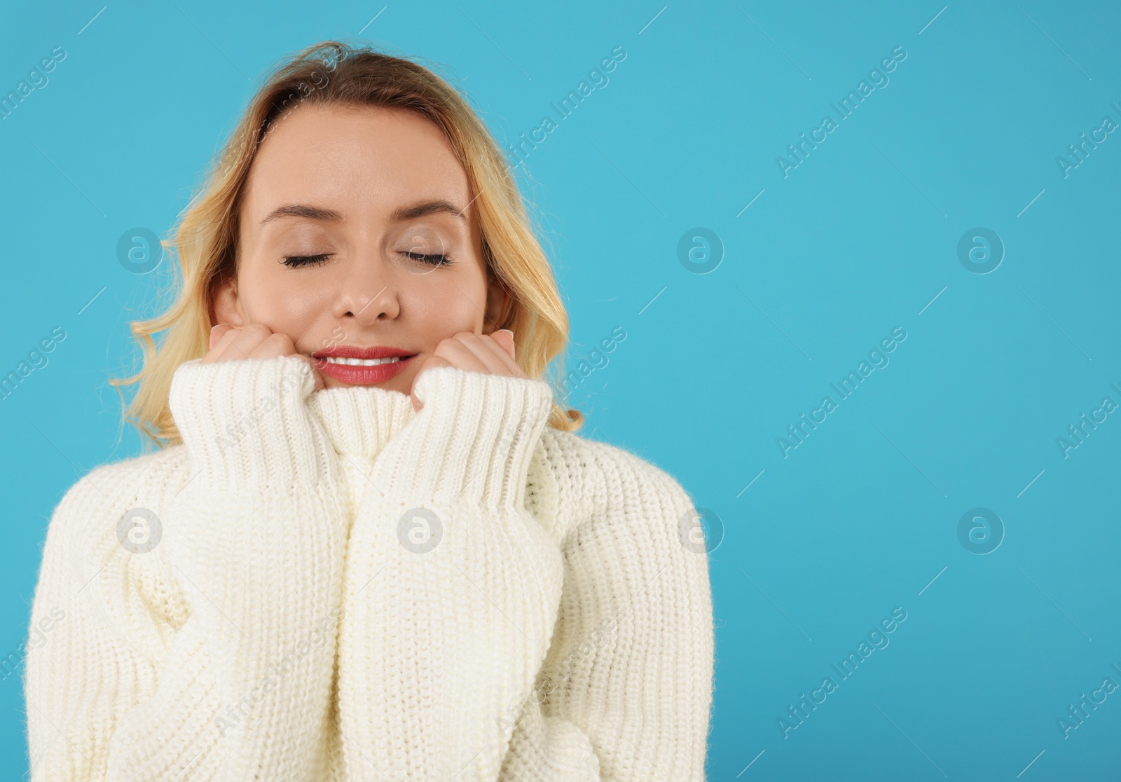 Photo of Beautiful woman in stylish warm sweater on light blue background. Space for text