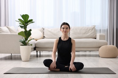 Beautiful girl meditating on yoga mat at home