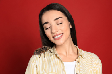 Woman with striped knee tarantula on red background. Exotic pet