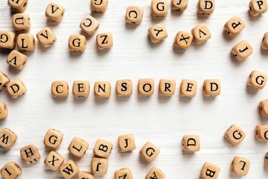 Photo of Wooden cubes with word Censored on white table, flat lay