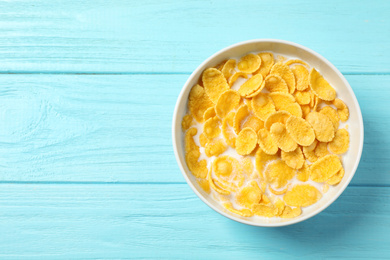 Photo of Tasty crispy corn flakes with milk on light blue wooden  table, top view. Space for text
