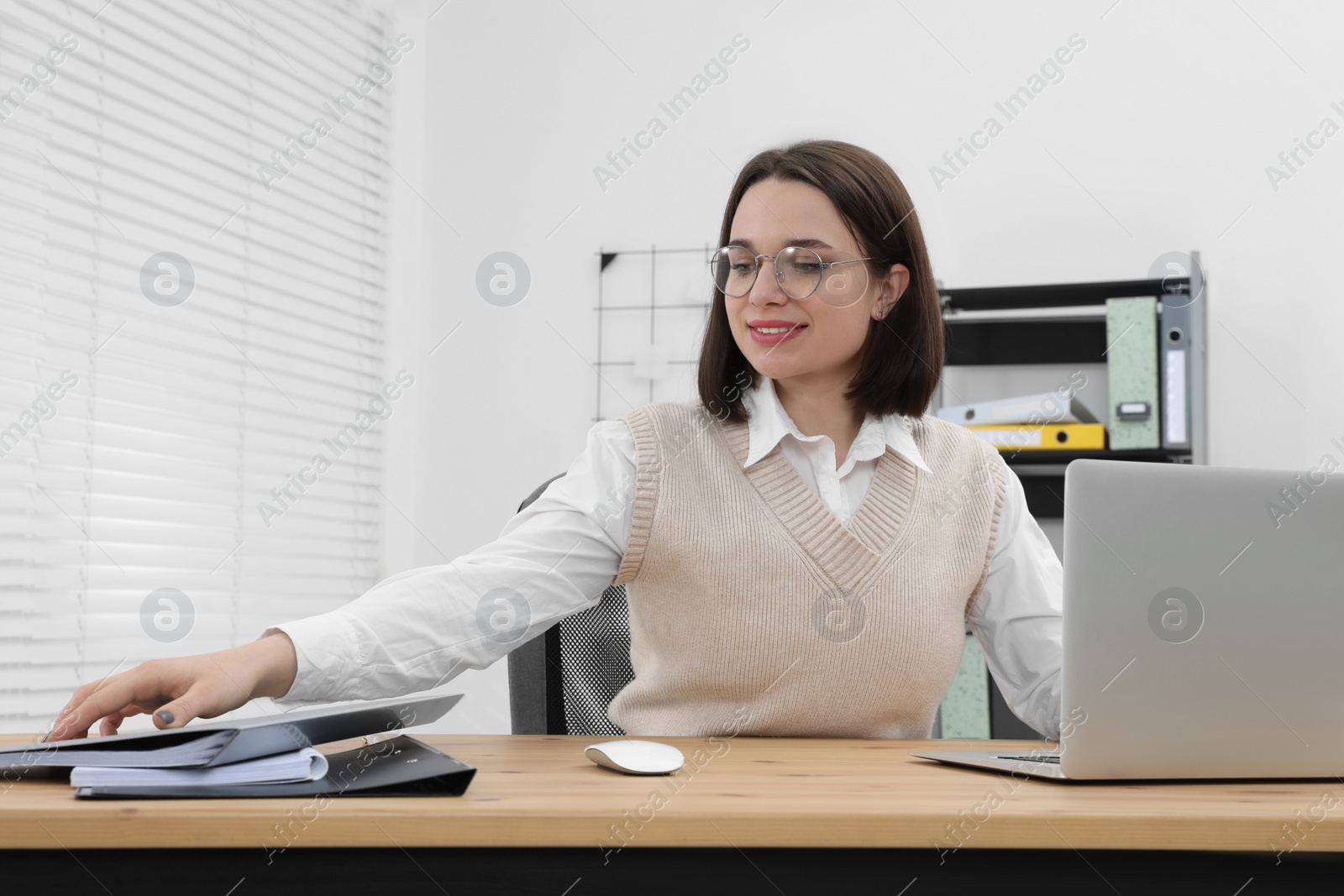 Photo of Happy young intern working at table in modern office