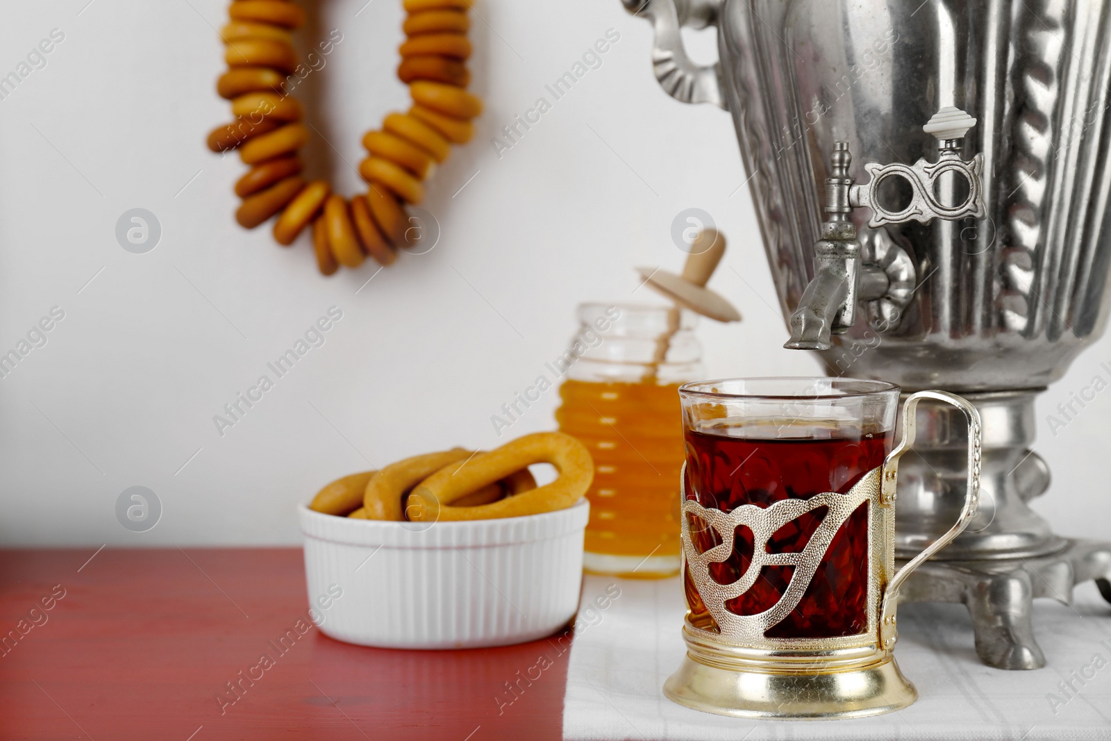 Photo of Composition with delicious ring shaped Sushki (dry bagels) and tea on brown table near white wall