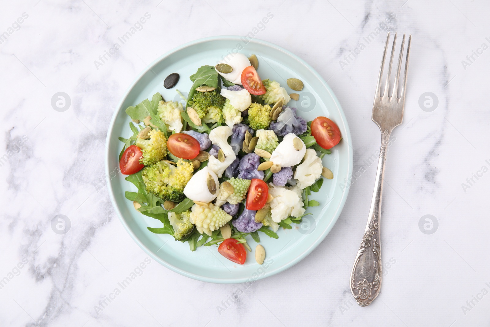 Photo of Delicious salad with cauliflower, tomato and cheese served on white marble table, flat lay