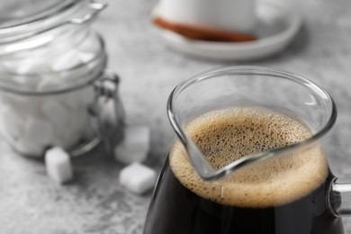 Photo of Turkish coffee in glass cezve on light grey table, closeup. Space for text