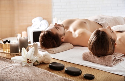 Young couple with spa essentials in wellness center