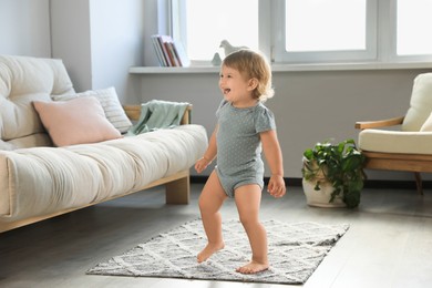 Cute baby learning to walk in living room