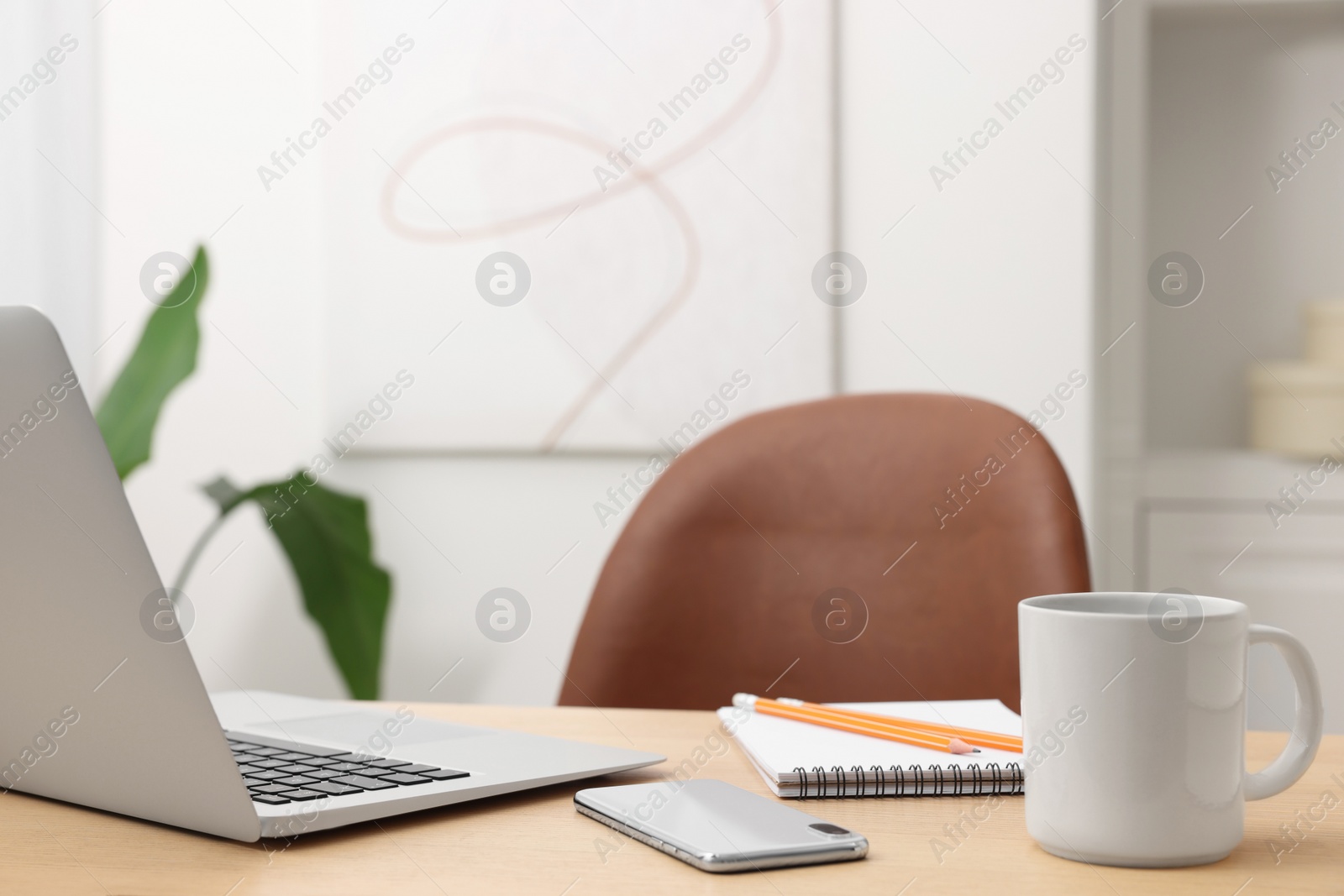 Photo of Home office. Laptop, cup, smartphone and stationery on wooden desk indoors. Space for text