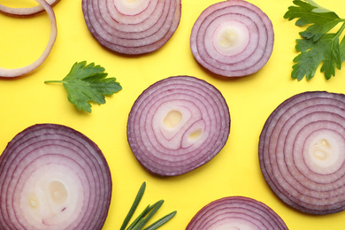 Flat lay composition with slices of onion and spices on yellow background