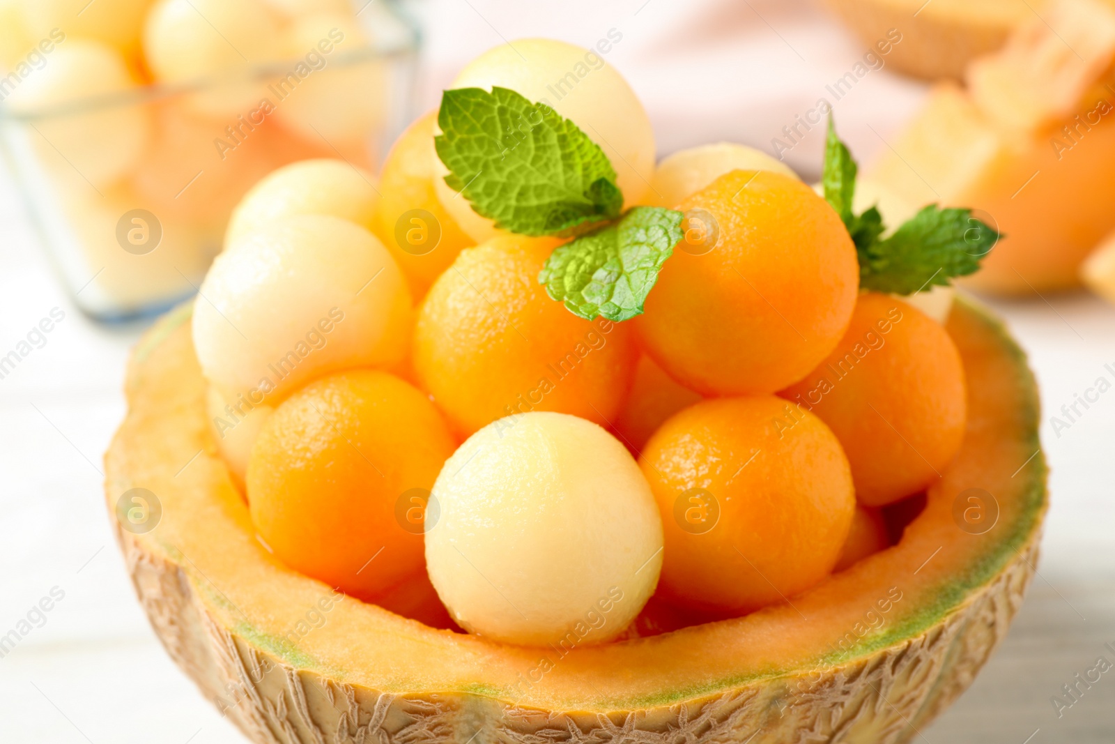 Photo of Different melon balls with mint on white table, closeup
