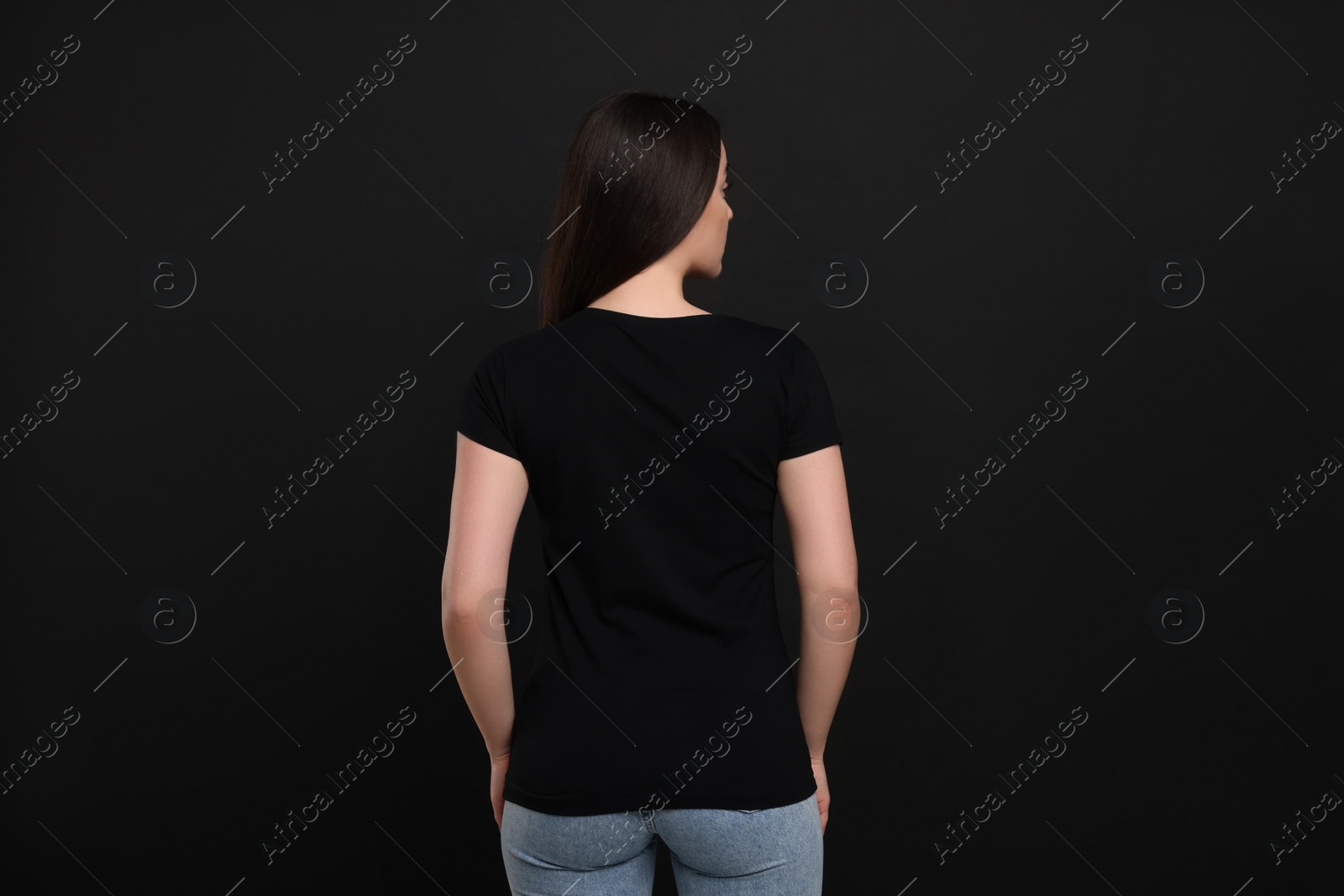 Photo of Woman wearing black t-shirt on dark background, back view