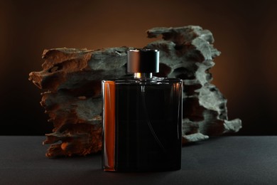 Photo of Luxury men`s perfume in bottle on grey table against brown background